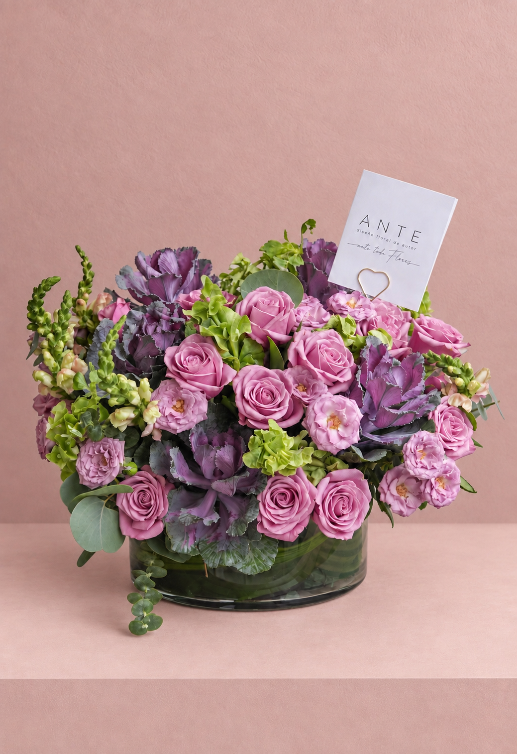 Arreglo floral con col ornamental morada, rosas rosas y hortensia verde en florero de vidrio bajo, entrega a domicilio CDMX