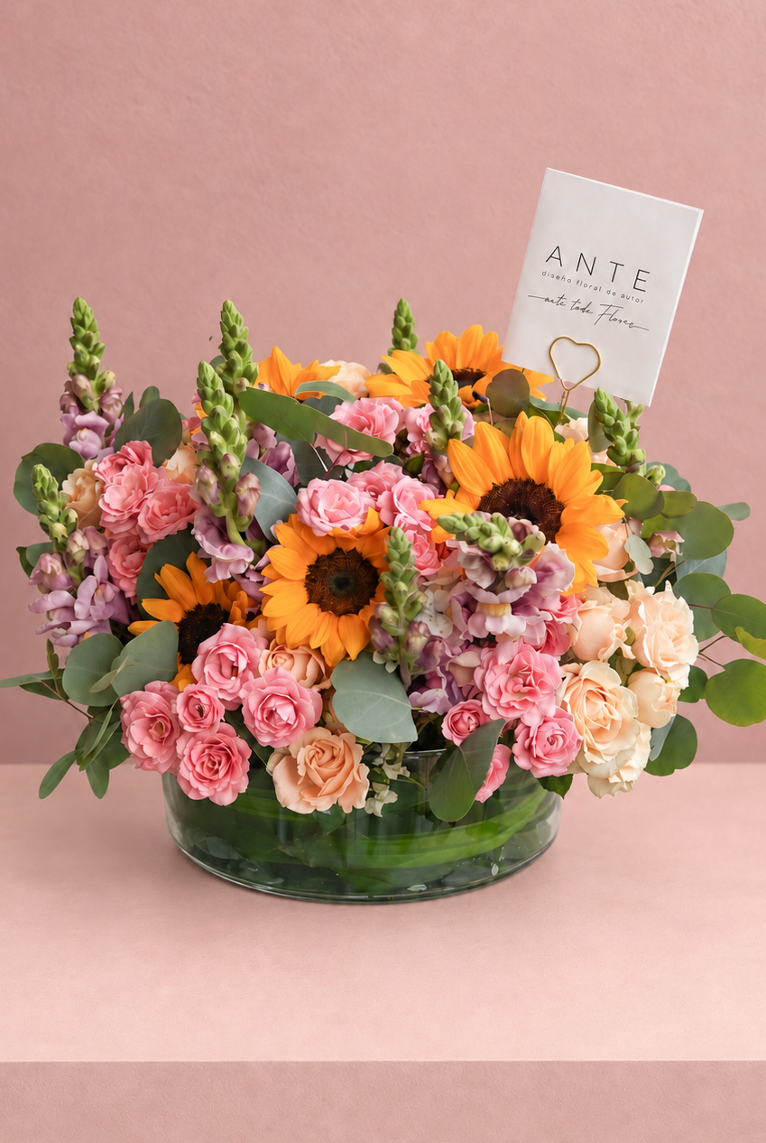 Arreglo floral con girasoles, alhelí lila y rosas spray rosa y durazno en florero de vidrio bajo, entrega a domicilio CDMX