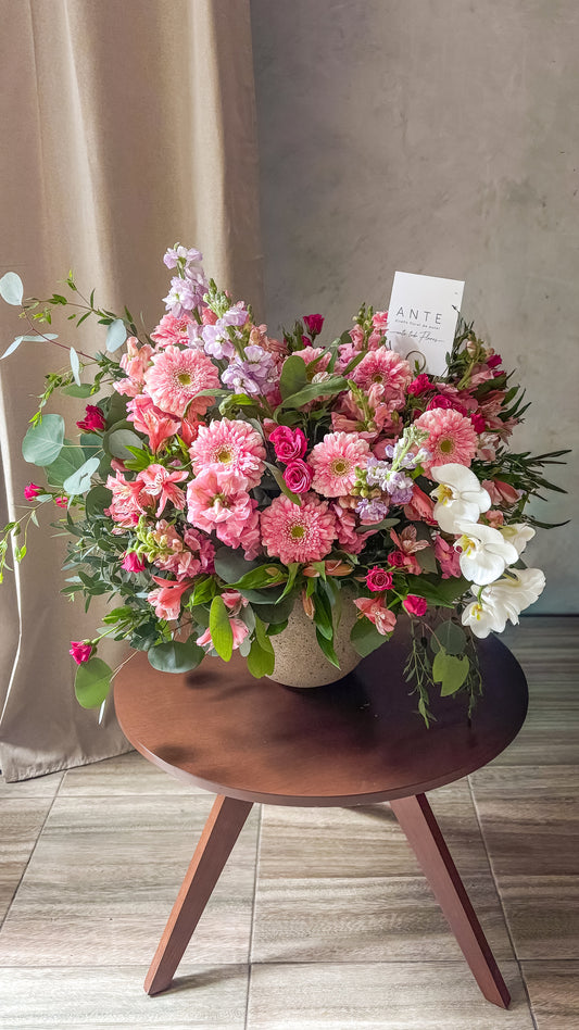 Arreglo floral rosa con gerberas, alstromerias, mini rosas, alhelí lila y orquídea blanca en cascada en florero de cerámica, entrega a domicilio CDMX