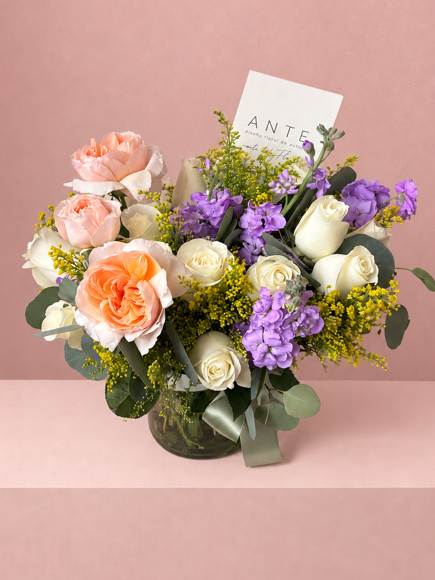 
Arreglo floral con rosas jardín durazno, rosas blancas y alhelí lila en florero de vidrio con moño verde, entrega a domicilio CDMX