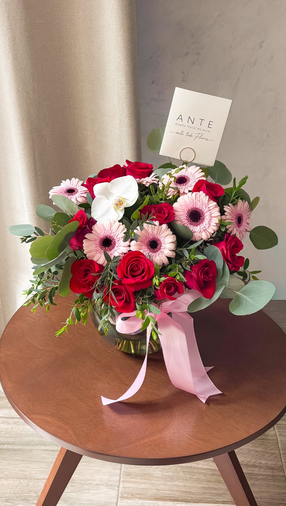 Arreglo floral con rosas rojas, gerberas rosa claro y orquídea blanca con eucalipto en florero de vidrio con moño rosa, entrega a domicilio CDMX