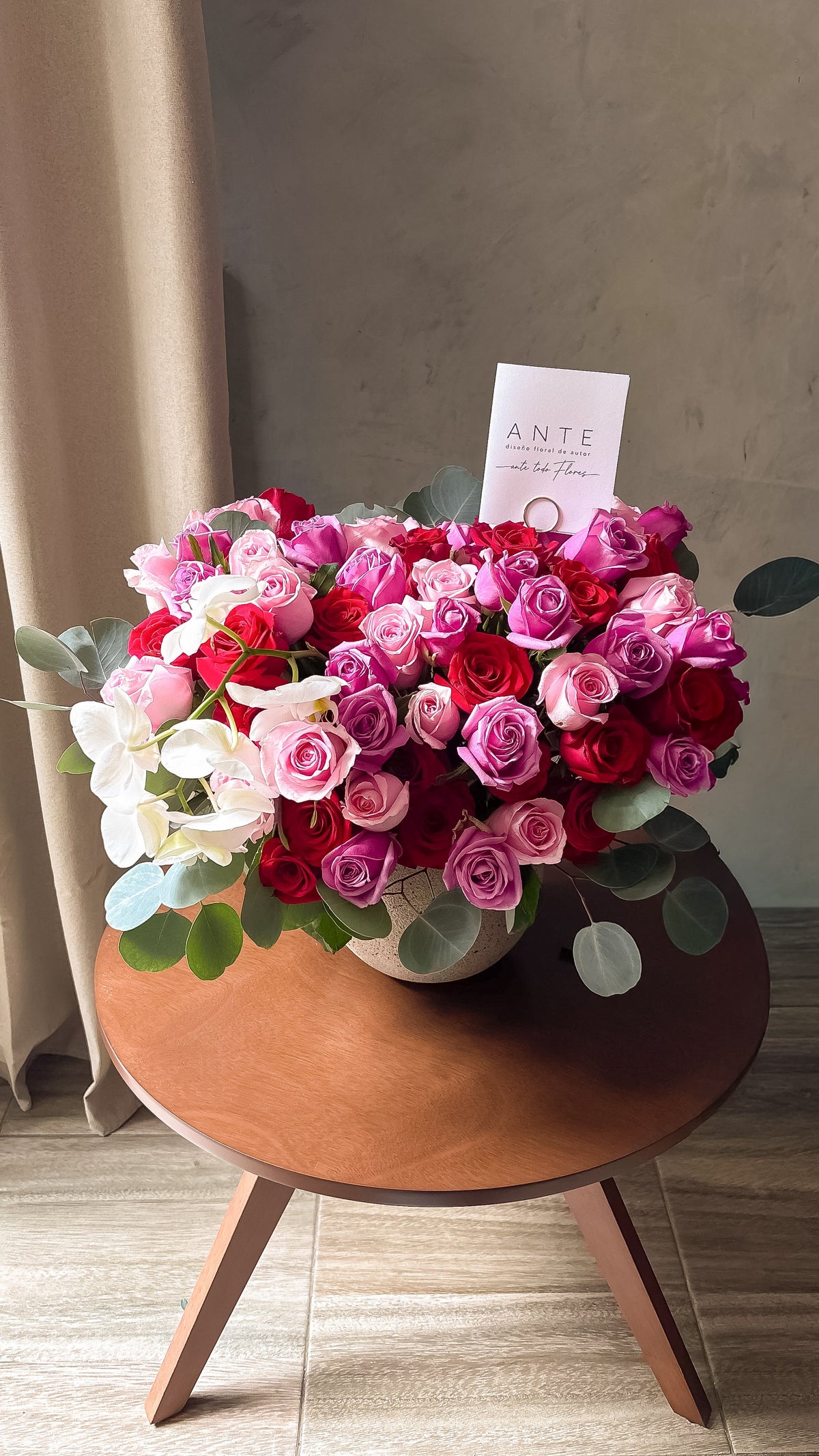 Arreglo de rosas rojas, rosas y moradas con orquídeas blancas en cascada en florero cerámico gris, entrega a domicilio CDMX