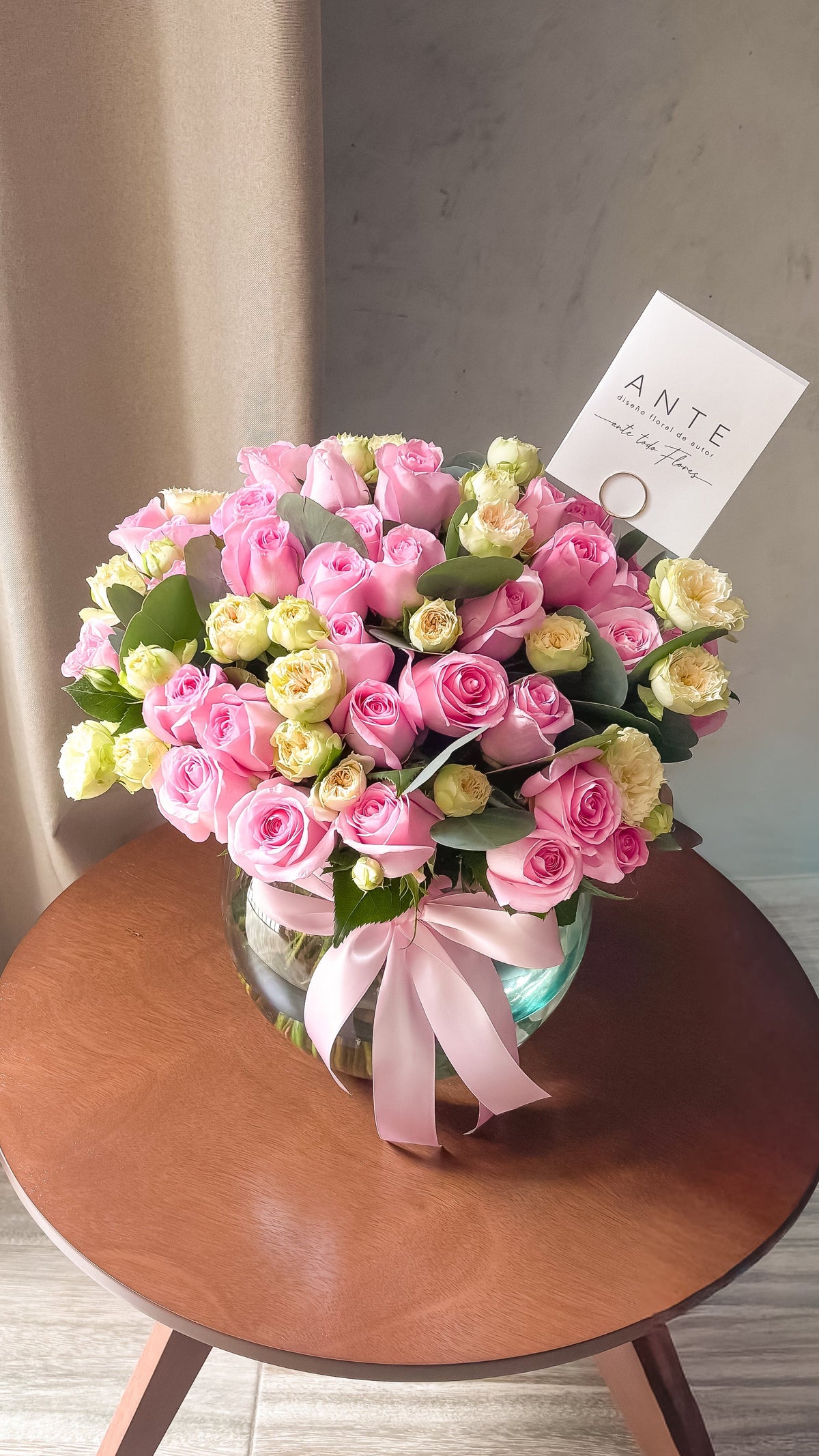 Arreglo de rosas rosa claro y mini rosas spray crema con eucalipto en florero de vidrio redondo con moño rosa, entrega a domicilio CDMX
