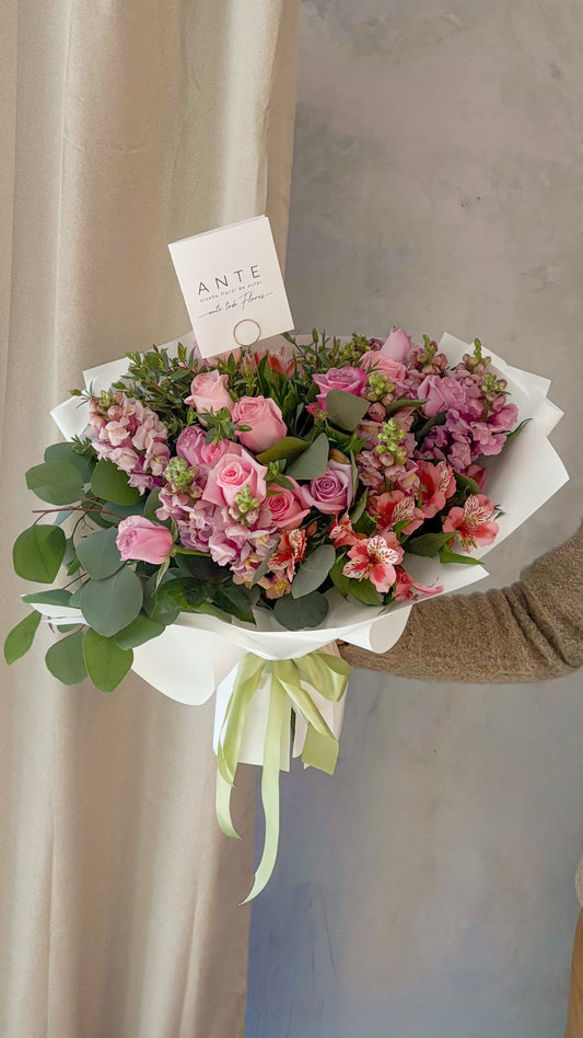 Ramo de flores lilas y rosas con rosas, perritos, alhelí y alstromerias fucsia en envoltura blanca con listón verde salvia, entrega a domicilio CDMX